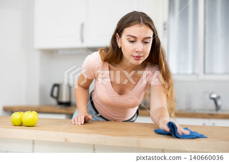 Woman cleaning dinning table with rag in kitchen at home 140660036