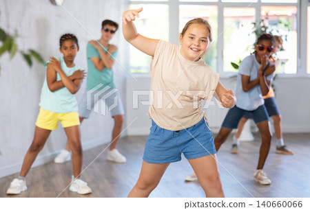 Girl perform choreographic exercises and teach energetic social dance waacking with friends Girl perform choreographic exercises and teach energetic social dance waacking with friends 140660066
