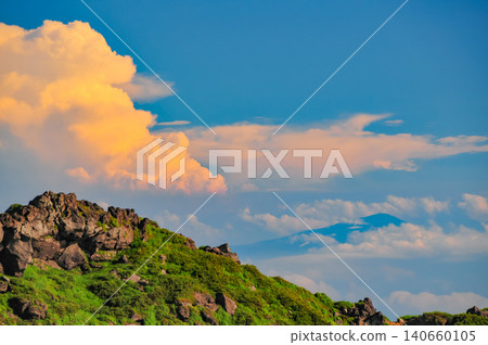 A summer evening view from near the Omuro Hut on Mt. Chokai, showing the orange sunset clouds and the silhouette of Mt. Gassan. A summer evening view from near the Omuro Hut on Mt. Chokai, showing the orange sunset clouds and the silhouette of Mt. Gassan. 140660105