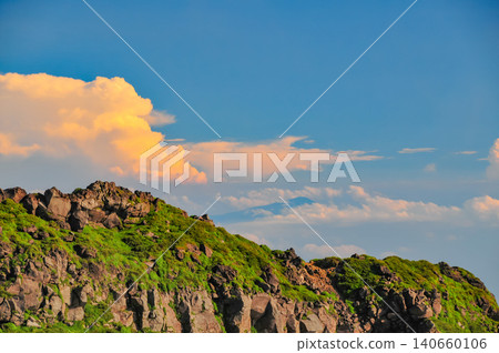 A summer evening view from near the Omuro Hut on Mt. Chokai, showing the orange sunset clouds and the silhouette of Mt. Gassan. 140660106