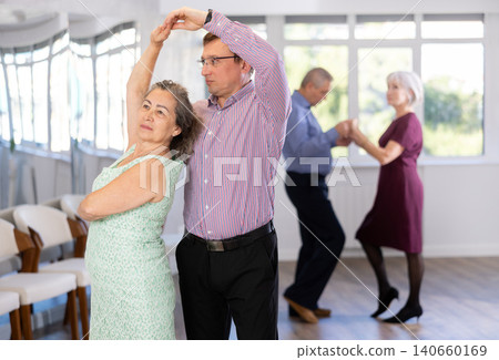 Middle-aged man and elderly woman are dancing classic version of waltz in couple. Middle-aged man and elderly woman are dancing classic version of waltz in couple. 140660169