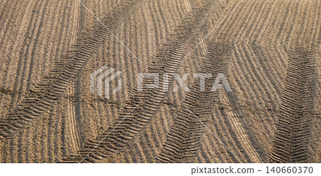 A landscape with tractor tire tracks remaining in a tilled field. A landscape with tractor tire tracks remaining in a tilled field. 140660370
