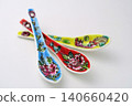 A white background with colorful Peranakan ceramic teaspoons. 140660420