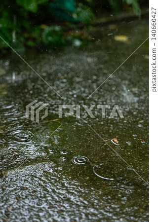Concept of rainwater harvesting, water conservation, sustainable resource management, eco-friendly living and efficient use of natural rainfall. The scene shows dripping water from residential roofing Concept of rainwater harvesting, water conservation, sustainable resource management, eco-friendly living and efficient use of natural rainfall. The scene shows dripping water from residential roofing 140660427