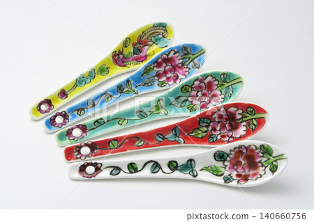 A white background with colorful Peranakan ceramic teaspoons. 140660756