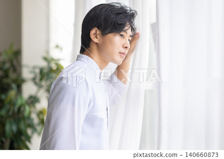 A man looking out the window 140660873