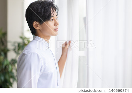 A man looking out the window 140660874