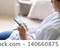 A man's hand looking at a smartphone 140660875