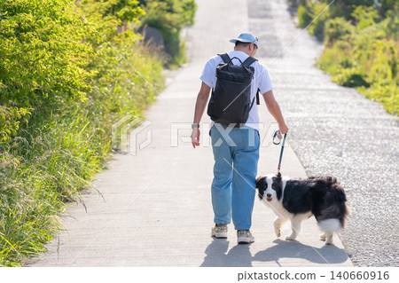 A man walking his Border Collie from behind. 140660916