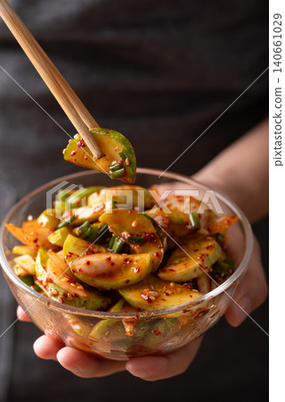 Korean cucumber salad in a glass bowl holding by woman hand and eating by using chopsticks Korean cucumber salad in a glass bowl holding by woman hand and eating by using chopsticks 140661029