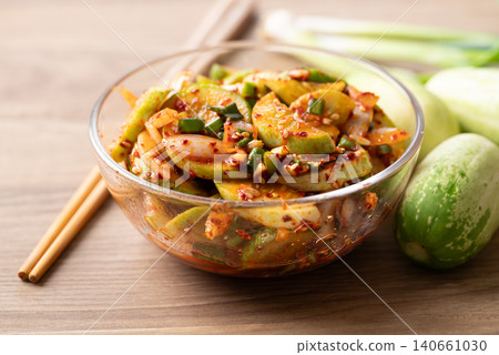 Korean cucumber salad in a glass bowl and chopsticks on wooden background Korean cucumber salad in a glass bowl and chopsticks on wooden background 140661030