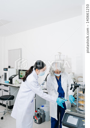 Two professional scientists conducting food quality testing and laboratory analysis in a modern research facility. Two professional scientists conducting food quality testing and laboratory analysis in a modern research facility. 140661250