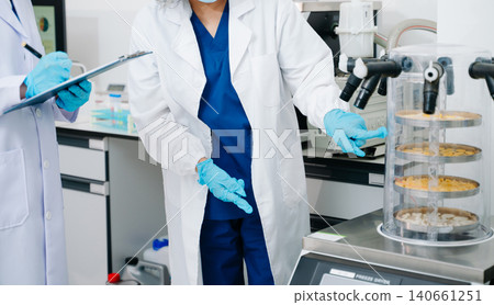 Two professional scientists conducting food quality testing and laboratory analysis in a modern research facility. Two professional scientists conducting food quality testing and laboratory analysis in a modern research facility. 140661251