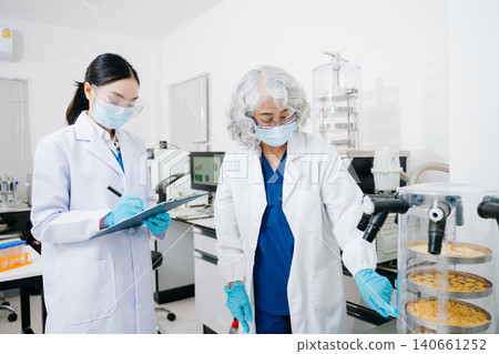Two professional scientists conducting food quality testing and laboratory analysis in a modern research facility. Two professional scientists conducting food quality testing and laboratory analysis in a modern research facility. 140661252