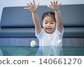 Young Asian girl playing with tennis balls at home, smiling and having fun during a casual indoor activity in a modern living room setting 140661270