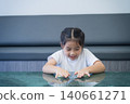 Young girl with braided hair expressing boredom or frustration while resting her chin on crossed arms at a modern office desk in a contemporary workspace 140661271