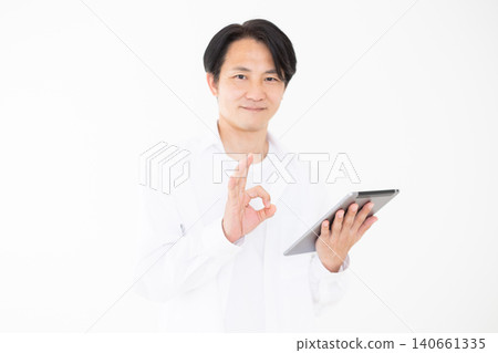 一位身穿白襯衫的中年男子在白色背景前,一邊看著平板電腦一邊做圓週運動。 一位身穿白襯衫的中年男子在白色背景前,一邊看著平板電腦一邊做圓週運動。 140661335