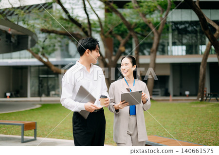 Professional business team collaborating outdoors with laptop and tablet, showcasing teamwork, communication, and modern corporate lifestyle 140661575