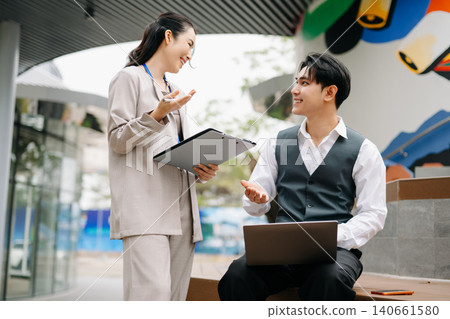 Two successful business colleagues having a discussion while talking on street in city Outside Two successful business colleagues having a discussion while talking on street in city Outside 140661580