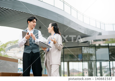 Businessman and woman going in city center in smart casual business style, talking, working together, stylish freelance people, holding coffee and laptop,tablet Businessman and woman going in city center in smart casual business style, talking, working together, stylish freelance people, holding coffee and laptop,tablet 140661587
