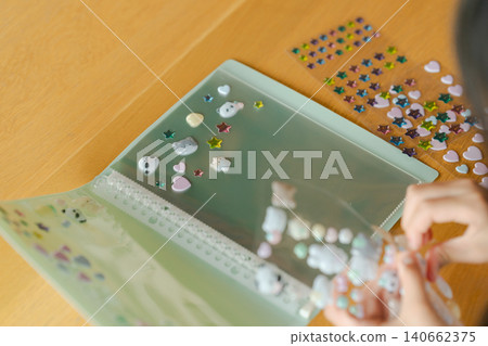 一個女孩的手在玩貼紙書 一個女孩的手在玩貼紙書 140662375