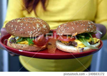 closeup of homemade hamburger in hands of woman 140663172