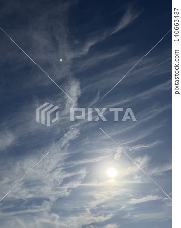 Cirrus clouds spread across the blue sky, and the sun shines brightly. 140663487