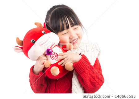 Smiling little girl hugging a red ox plush toy, celebrating the Year of the Ox, Chinese New Year theme.The Chinese character embroidered above: "Fu" (Good Fortune) Smiling little girl hugging a red ox plush toy, celebrating the Year of the Ox, Chinese New Year theme.The Chinese character embroidered above: "Fu" (Good Fortune) 140663583