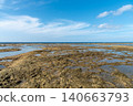 A clear blue sky and a shallow beach with tide pools still remaining. 140663793