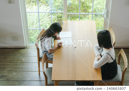 A girl doing her homework and her mother watching over her. A girl doing her homework and her mother watching over her. 140663807