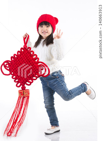 Happy Asian little girl holding a large Chinese knot ornament isolated on white background, celebrating Lunar New Year.There is a Chinese character on it: "Fu" (Good Fortune). 140663913