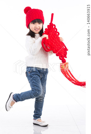 Happy Asian little girl holding a large Chinese knot ornament isolated on white background, celebrating Lunar New Year.There is a Chinese character on it: "Fu" (Good Fortune). 140663915