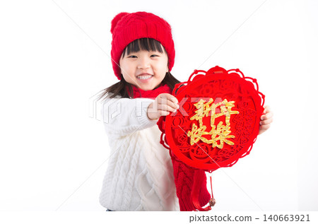 Little Chinese girl holding a red decoration with "Happy New Year" calligraphy, celebrating traditional spring festival. Little Chinese girl holding a red decoration with "Happy New Year" calligraphy, celebrating traditional spring festival. 140663921