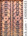 Old wooden gate leaf parts. Ancient wood door with metal rivets. Medieval wooden door with aged iron reinforcements 140664083
