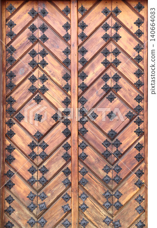 Old wooden gate leaf parts. Ancient wood door with metal rivets. Medieval wooden door with aged iron reinforcements 140664083