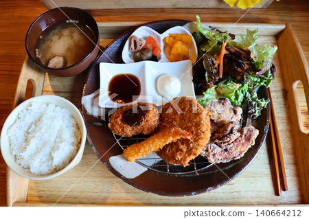 A Japanese set meal consisting of rice, miso soup, and fried food, served on a single plate. A Japanese set meal consisting of rice, miso soup, and fried food, served on a single plate. 140664212