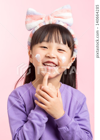 A cheerful studio portrait of a young Asian girl with long dark hair, bangs, and a striped headband, wearing a purple sweatshirt, smiling with patches of white face cream applied to her cheek, looking A cheerful studio portrait of a young Asian girl with long dark hair, bangs, and a striped headband, wearing a purple sweatshirt, smiling with patches of white face cream applied to her cheek, looking 140664285