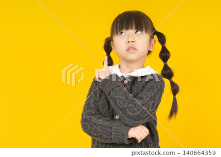 a thoughtful young girl in a dark grey sweater resting her chin on her finger and looking up pensively. a thoughtful young girl in a dark grey sweater resting her chin on her finger and looking up pensively. 140664359