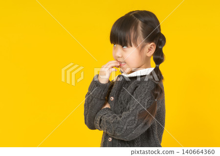 a thoughtful young girl in a dark grey sweater resting her chin on her finger and looking up pensively. a thoughtful young girl in a dark grey sweater resting her chin on her finger and looking up pensively. 140664360