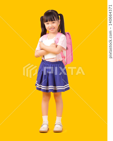 Confident young Asian girl in school uniform standing with crossed arms holding white notebook and wearing pink backpack Confident young Asian girl in school uniform standing with crossed arms holding white notebook and wearing pink backpack 140664371