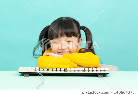 Tired little girl resting her head on crossed arms over a computer keyboard with eyes closed. Tired little girl resting her head on crossed arms over a computer keyboard with eyes closed. 140664373
