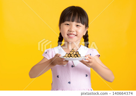 Smiling little girl showing a pyramid stack of seaweed rolls on a plate to camera 140664374