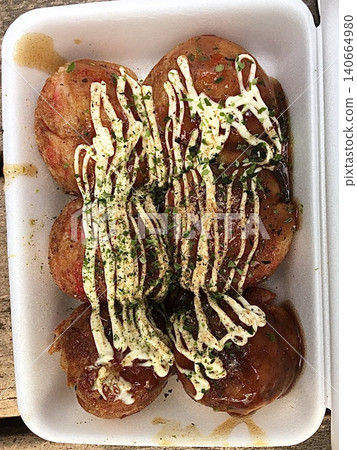 Takoyaki, a popular Japanese street food, are crispy round dough balls filled with octopus, tempura bits, and pickled ginger, topped with takoyaki sauce, bonito flakes, and aonori. Takoyaki, a popular Japanese street food, are crispy round dough balls filled with octopus, tempura bits, and pickled ginger, topped with takoyaki sauce, bonito flakes, and aonori. 140664980