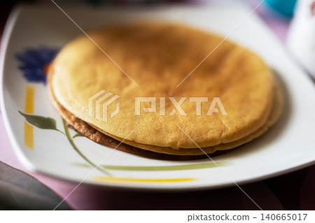 Stack of golden pancakes on patterned plate Stack of golden pancakes on patterned plate 140665017
