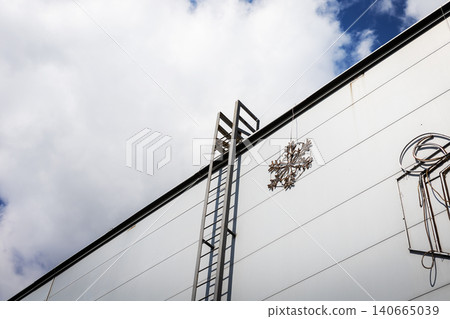 Metal ladder rising along white cargo trailer under cloudy sky Metal ladder rising along white cargo trailer under cloudy sky 140665039