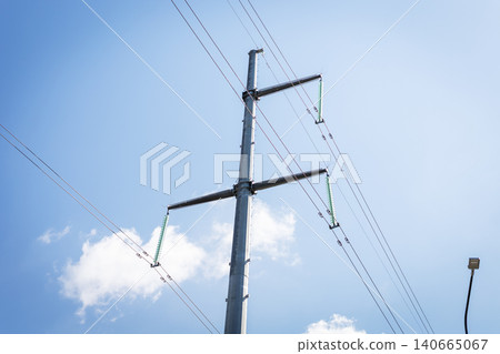High voltage transmission pole against blue sky with scattered clouds High voltage transmission pole against blue sky with scattered clouds 140665067