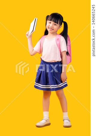 Smiling Asian school girl holding book with backpack isolated on yellow background, confident emotion, education and reading concept Smiling Asian school girl holding book with backpack isolated on yellow background, confident emotion, education and reading concept 140665245