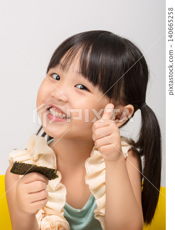 Happy Asian kid holding a piece of seaweed snack, healthy dried seaweed concept for children. Happy Asian kid holding a piece of seaweed snack, healthy dried seaweed concept for children. 140665258