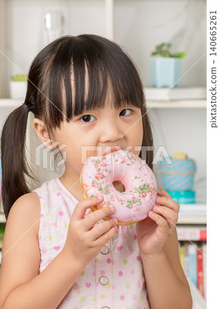Portrait of a little girl eating a large pink glazed donut, unhealthy sugary snack for kids. Portrait of a little girl eating a large pink glazed donut, unhealthy sugary snack for kids. 140665261