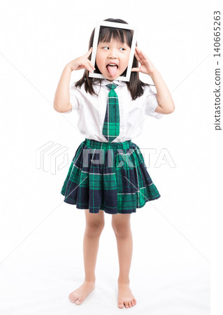 Playful Asian girl in school uniform looking through a white frame making a funny face. 140665263